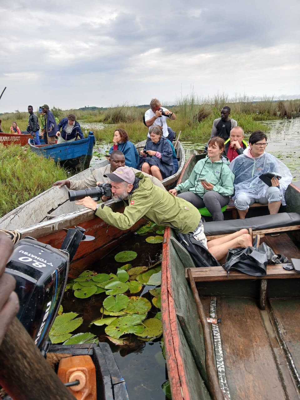 Image of tourists using binoculars to vew birds in a boat ride to Mabamba swamp on lake Victoria