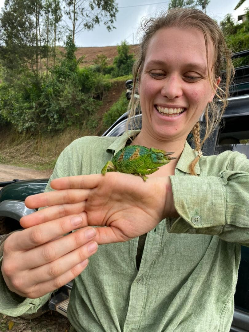 Image of a happy tourist lady holding a three horned chameleon